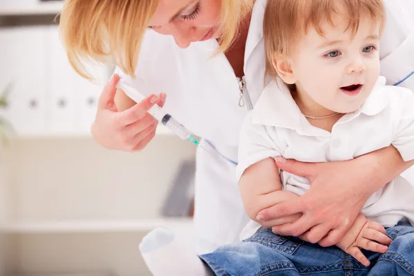 Doctor giving a child injection in arm — Stock Photo, Image