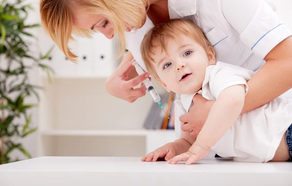 Médico inyectando a un niño en el brazo —  Fotos de Stock