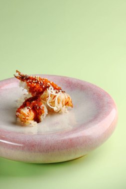 Seramik tabakta karides tempura yeşil arka planda yakın plan.