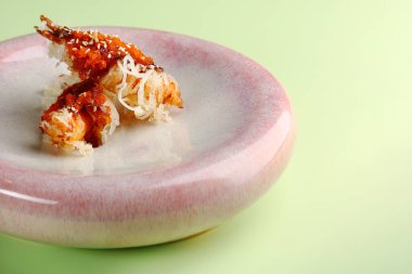 Seramik tabakta karides tempura yeşil arka planda yakın plan.