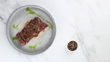 Izgara sığır eti bifteği manzaralı. Kırmızı biberli dilimlenmiş biftek ve yeşil ışık mermer arka planda fotokopi alanı ile..