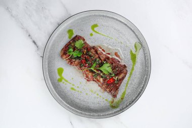 Izgara sığır eti bifteği manzaralı. Kırmızı biberli dilimlenmiş biftek ve yeşil ışık mermer arka planda fotokopi alanı ile..