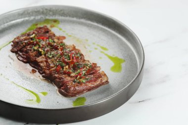 Izgara sığır eti bifteği yakın plan. Seramik tabakta kırmızı biberli dilimlenmiş biftek..