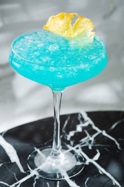 Cam yaz içeceği konseptinde Mavi Hawaii Kokteyli. Mermer masada ananaslı mavi kokteyl..