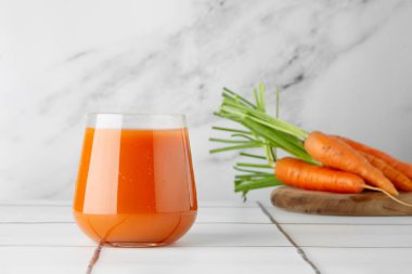 Masada taze havuç suyu ve ahşap güvertede taze havuç.