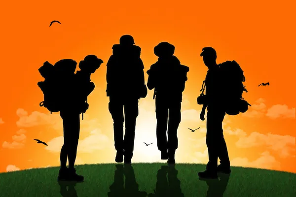 Günbatımında bir tepe üstünde yürüyen backpackers grubu