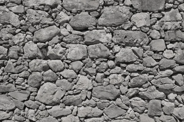 Parede velha cinza escuro feito de pedras grandes e pequenas — Fotografia de Stock