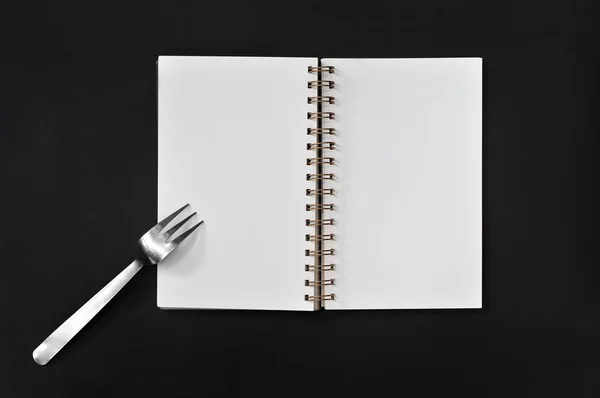 Blank notepad with fork on black background — Stock Photo, Image