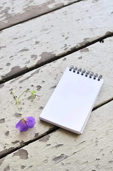 Tom anteckningsbok och violett blomma på rustik plank trä bakgrund — Stockfoto