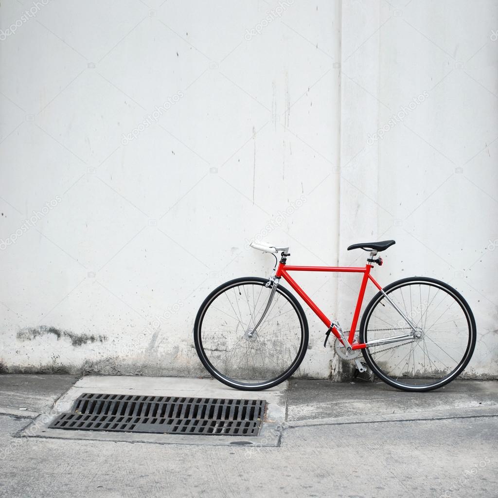 Modern red bicycle leaning on white wall