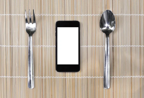 Smartphone with fork and spoon on bamboo mat background — Stock Photo, Image