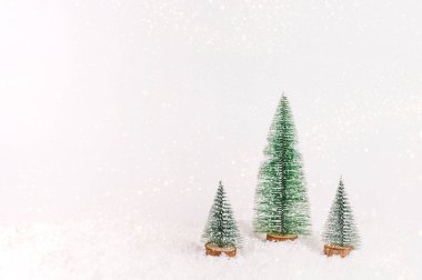 Beyaz karlı arka planda minyatür noel ağaçları. Yeni yıl konsepti. Boşluğu kopyala, ön görünüm