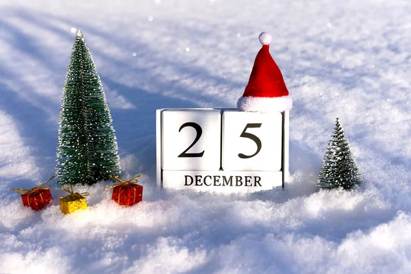 Concepto de Navidad. 25 de diciembre números de calendario y sombrero de Santa sobre fondo de nieve con luces. —  Fotos de Stock