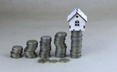 Bozuk paraların üzerinde minyatür ahşap bir ev. Mülk, bankacılık ve finans kavramları, gayrimenkul edinimi