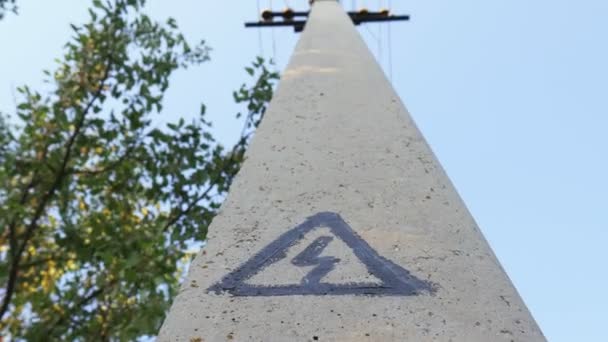 Знак опасности на бетонной колонне. Электрическая поддержка для подвешивания проводов — стоковое видео