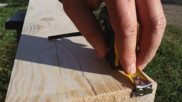 Using a ruler, the worker marks the dimensions with a pencil. Yellow tape measure, roll of measuring tape. Preparing the dimensions of the board for subsequent processing — 图库视频影像