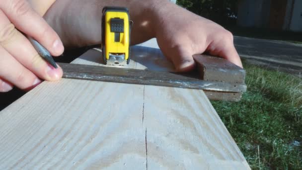 Pracovník pomocí pravítka označí rozměry tužkou. Žlutá páska, role měřicí pásky. Příprava rozměrů desky pro následné zpracování — Stock video