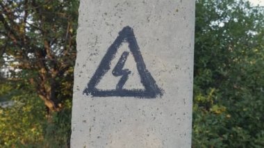 Beton bir sütunda tehlike işareti. Asma kablolar için elektrik desteği