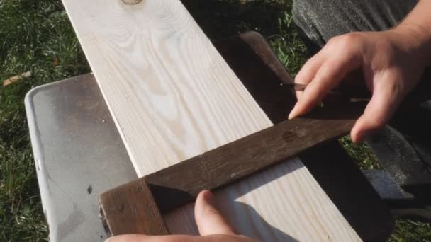 Mit einem Lineal markiert der Arbeiter die Maße mit einem Bleistift. Gelbes Maßband, Rolle Maßband. Vorbereitung der Abmessungen der Platte für die weitere Bearbeitung — Stockvideo