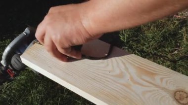 İşçi, cetvel kullanarak boyutları kurşun kalemle işaretliyor. Sarı mezura, mezura rulosu. Tahtanın boyutları sonraki işlem için hazırlanıyor