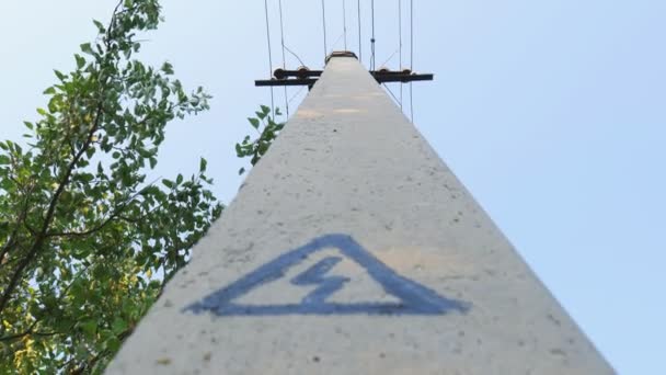 A hazard sign on a concrete pillar. Electrical support for hanging wires — Stockvideo