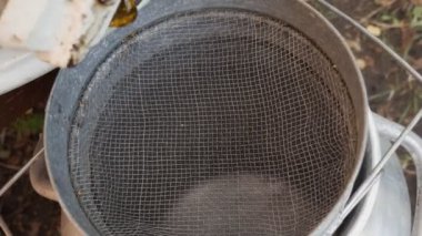 Bal sökücünün balı süzgeçten geçiriliyor. Bal fıçıdan kevgire dökülüyor.
