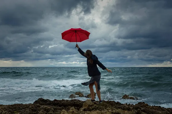 海の背景に赤い傘を持つ若い女性 発展途上のドレスで若い暗い髪の少女と大気の秋の風景 幸福の概念 — ストック写真