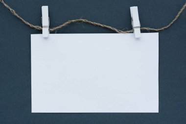 Modelleme. Gri arka planda beyaz bir not defteri. Mandallı çarşaf ve ip. Kavramsal iş minimalizmi. Reklamcılık, monokrom tasarım, şık iş afişi.