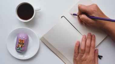 2022 not defteri kadın eli. Hedefler ve hedefler kavramı. Gelecek yıl için plan yapıyorum. Elinde kahve fincanı olan yaratıcı bir masaüstü görüntüsü. Pasta, Kaplan Yılı 'nın sembolüdür.