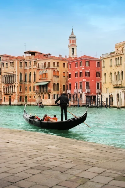 Venice: classic view of a romantic ride on a gondola boat in Grande Canale, near Rialto bridge, surrounded by historic buildings. — Stock Photo, Image