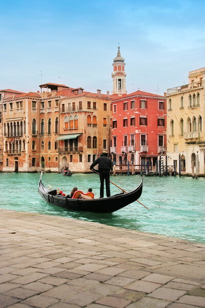 Venice: classic view of a romantic ride on a gondola boat in Grande Canale, near Rialto bridge, surrounded by historic buildings.