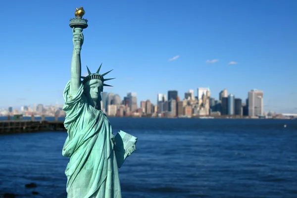纽约： 自由女神像、 美国的象征，与低曼哈顿天际线的背景。旅游概念照片。自由岛，纽约城，美国 免版税图库图片