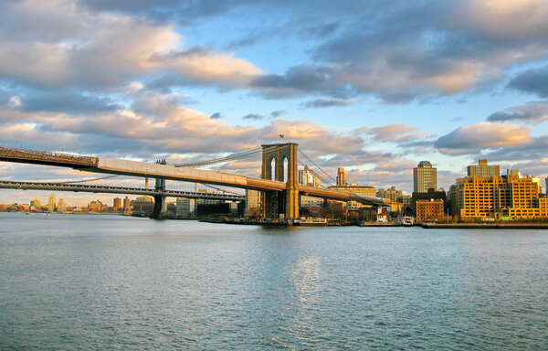 Brooklyn Bridge and East River at sunset, seen from historic Pier 17. New York City, USA