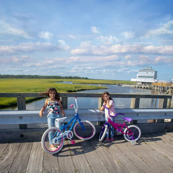 İki genç bisikletçi bir yaz gününde nehir köprüsünde duraklıyor.