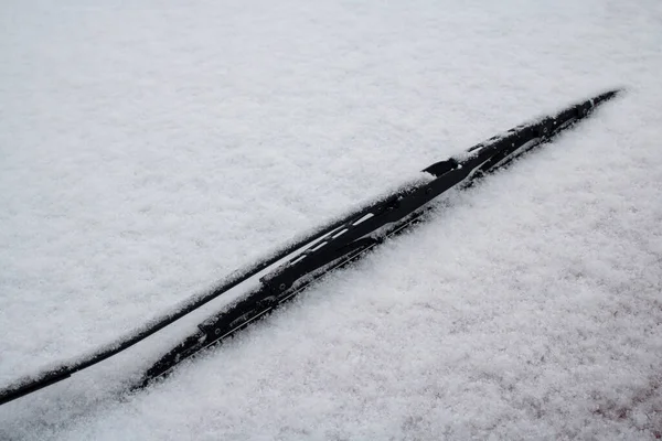car windshield with snow cover and bloack windshield wipper