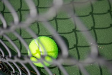 Açık yeşil topla tenis kortundaki bulanık Galvanizli Zincir Halka çitinden bakıyorum.