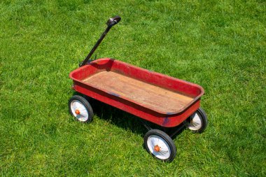 Rusty old red wagon parked at a yard decoration after the children have grown and moved on
