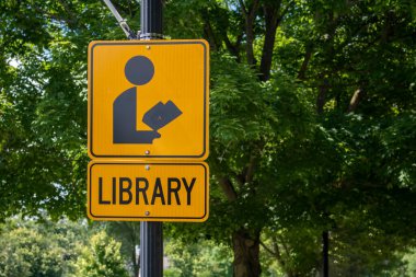 Sign of person reading a book with the word Library below. Black and yello rectangle sign