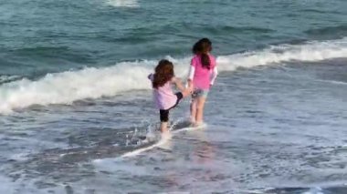 İki kız soğuk bir yaz gününde sahilde oynuyorlar.