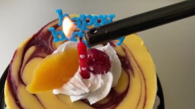 Kırmızı-beyaz benekli peynirli kek ve mutlu yıllar mavi plastik tipi. Bir mumlu çikolatalı cheesecake ve mutlu yıllar mavi plastik tipi.