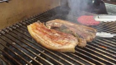 Elinde maşayla dışarıda ızgarada domuz eti pişiren adam.