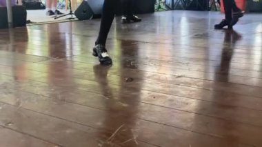 Siyah ve gümüş ayakkabılı genç bir kız geleneksel İrlanda step dansı yapıyor. Aziz Patrick Günü 'nde genç bir kız ahşap zeminde İrlanda dansı yapıyor.