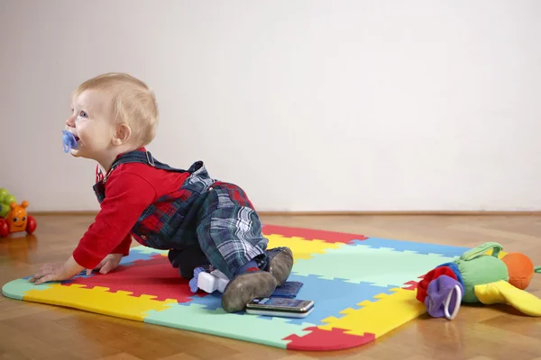 Mladý chlapec hraje vnitřní na dřevěnou podlahu — Stock fotografie