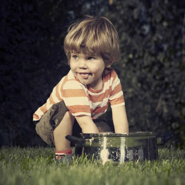 Jonge jongen thuis spelen in de buurt van huis in tuin met verschillende speelgoed — Stockfoto