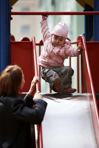 彼女の母親と一緒に遊んで遊び場で外の小さな女の子 — ストック写真