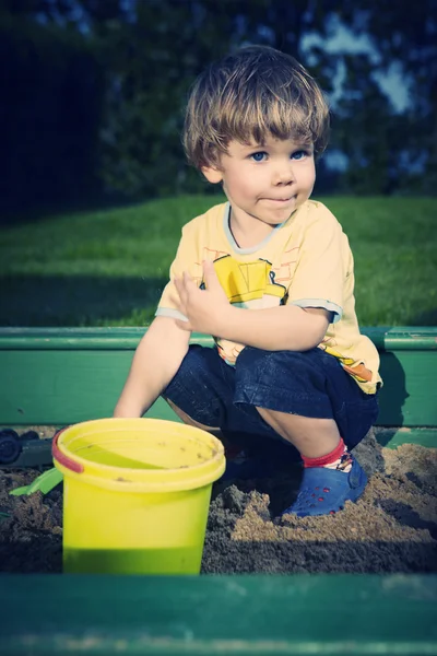 Jonge jongen thuis spelen in de buurt van huis in tuin met verschillende speelgoed — Stockfoto