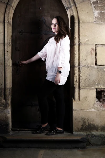 Jovem senhora peituda posando ao ar livre pela igreja para retratos em top branco — Fotografia de Stock