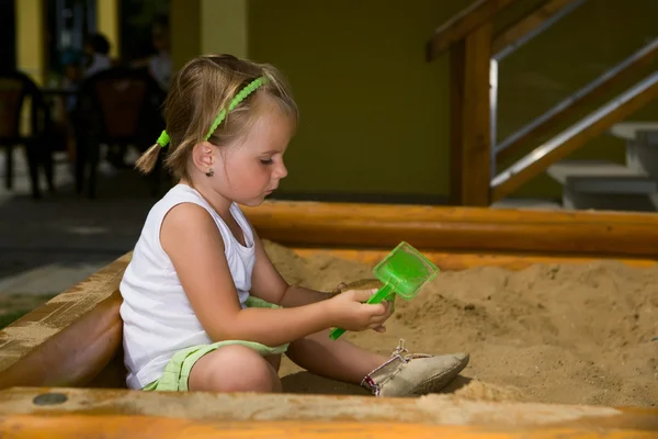 Маленькая девочка играет на песочнице — стоковое фото