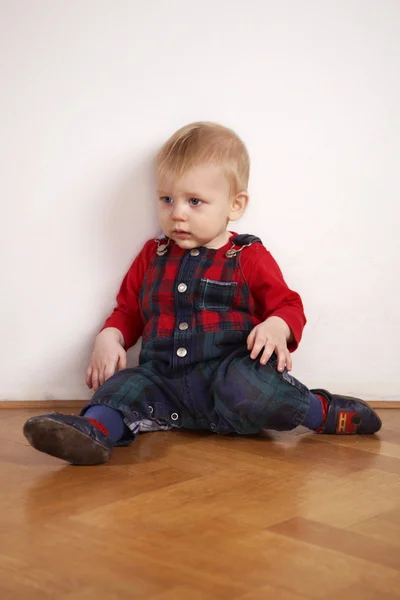 Young boy playing indoor on wooden floor — Stock Photo, Image