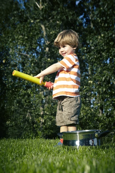 Young boy playing at home near house in garden with various toys — Stock Photo, Image